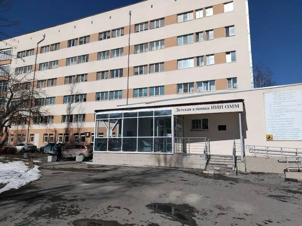 Вход в Детскую клинику НИИ ОММ: шестиэтажное здание, стеклянное крыльцо и вывеска «Детская клиника НИИ ОММ» над входом